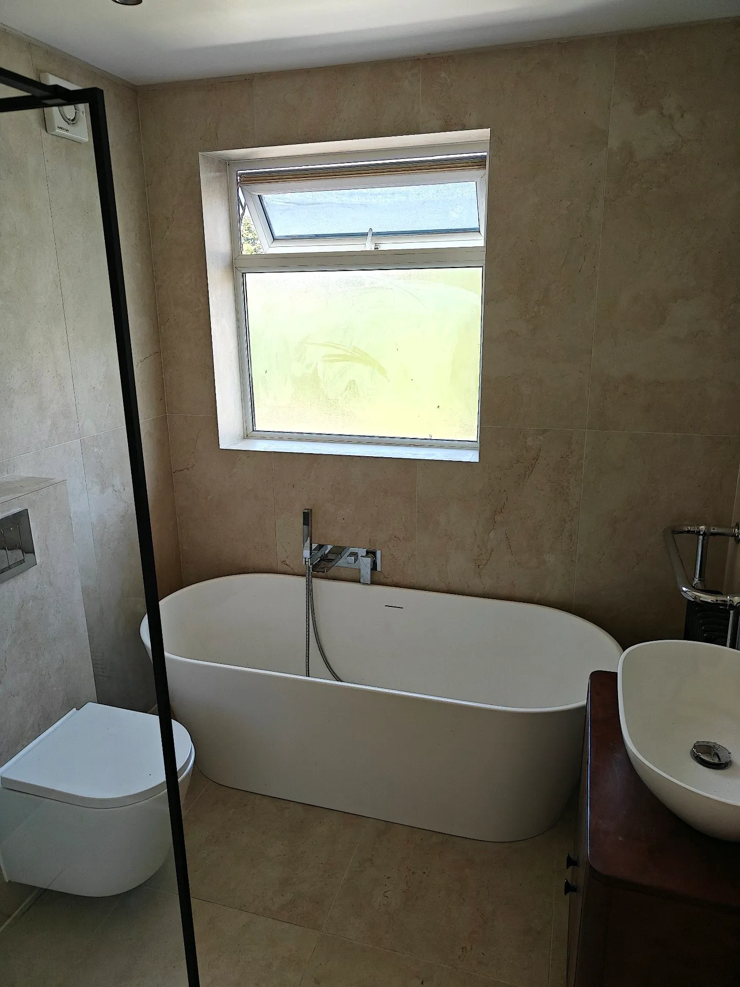 Wide view of a completed sandstone-tiled bathroom by GWS with a walk-in shower and vanity unit