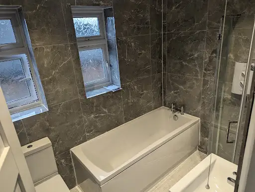 Brown marble bathroom with bath and glass shower screen