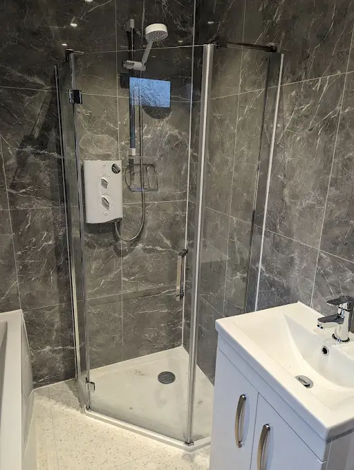 Dark marble bathroom with corner shower enclosure