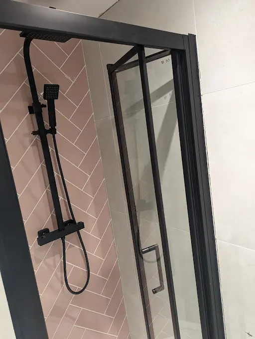 Pink herringbone tile shower with black frame enclosure