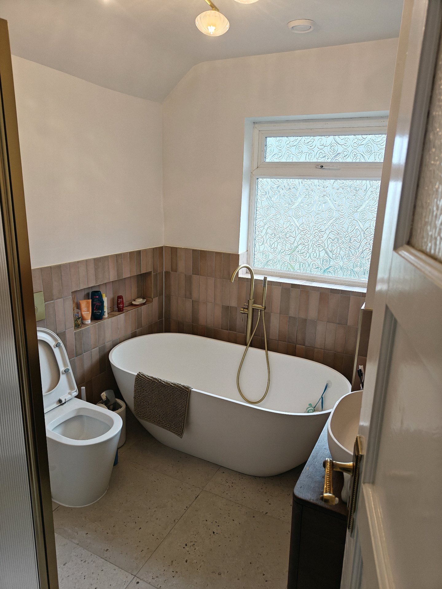 After: Modern bathroom with freestanding tub, terracotta tiles, brass fixtures