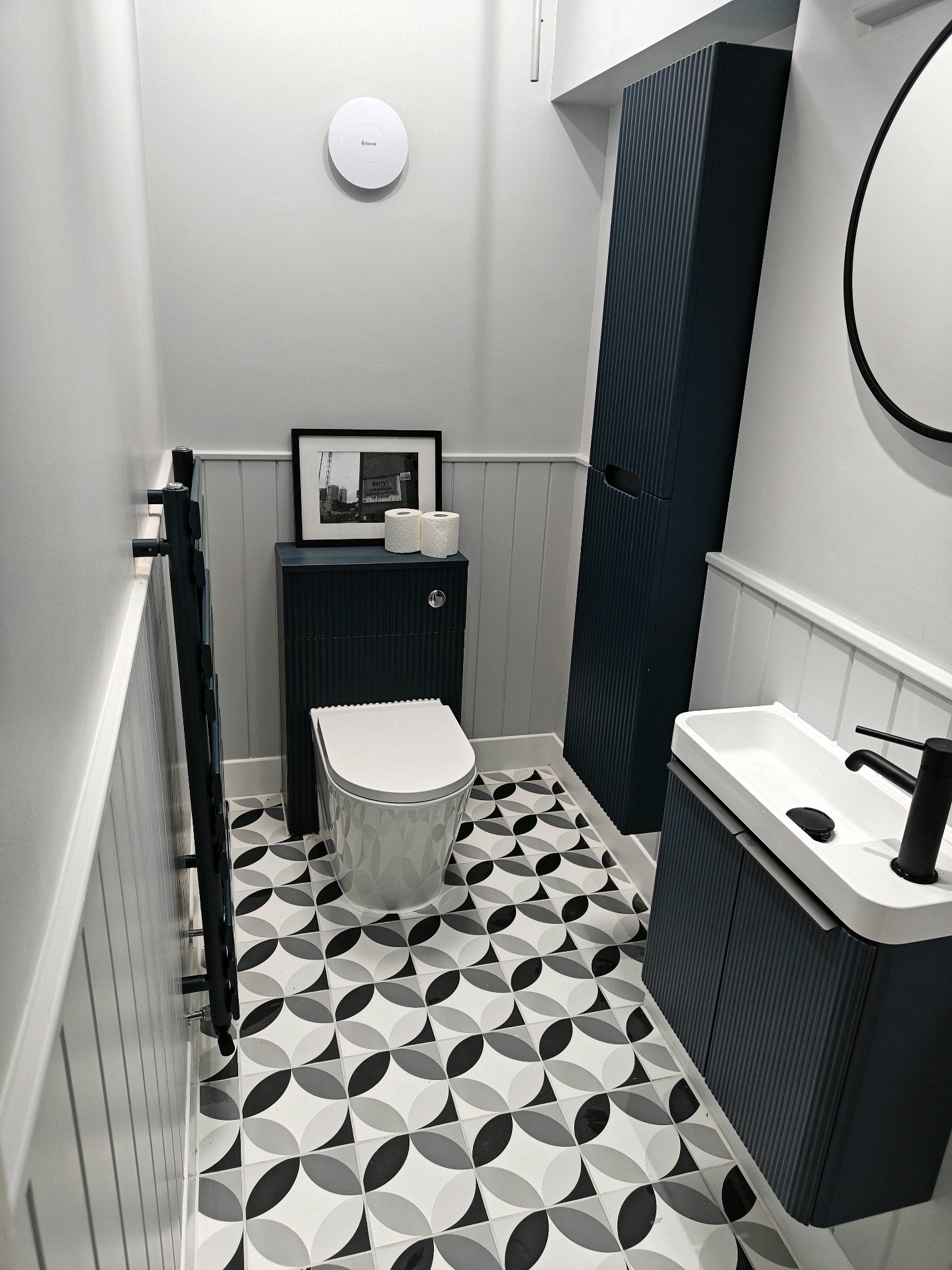 After: Stylish cloakroom with navy fluted units, geometric floor tiles, white panelling