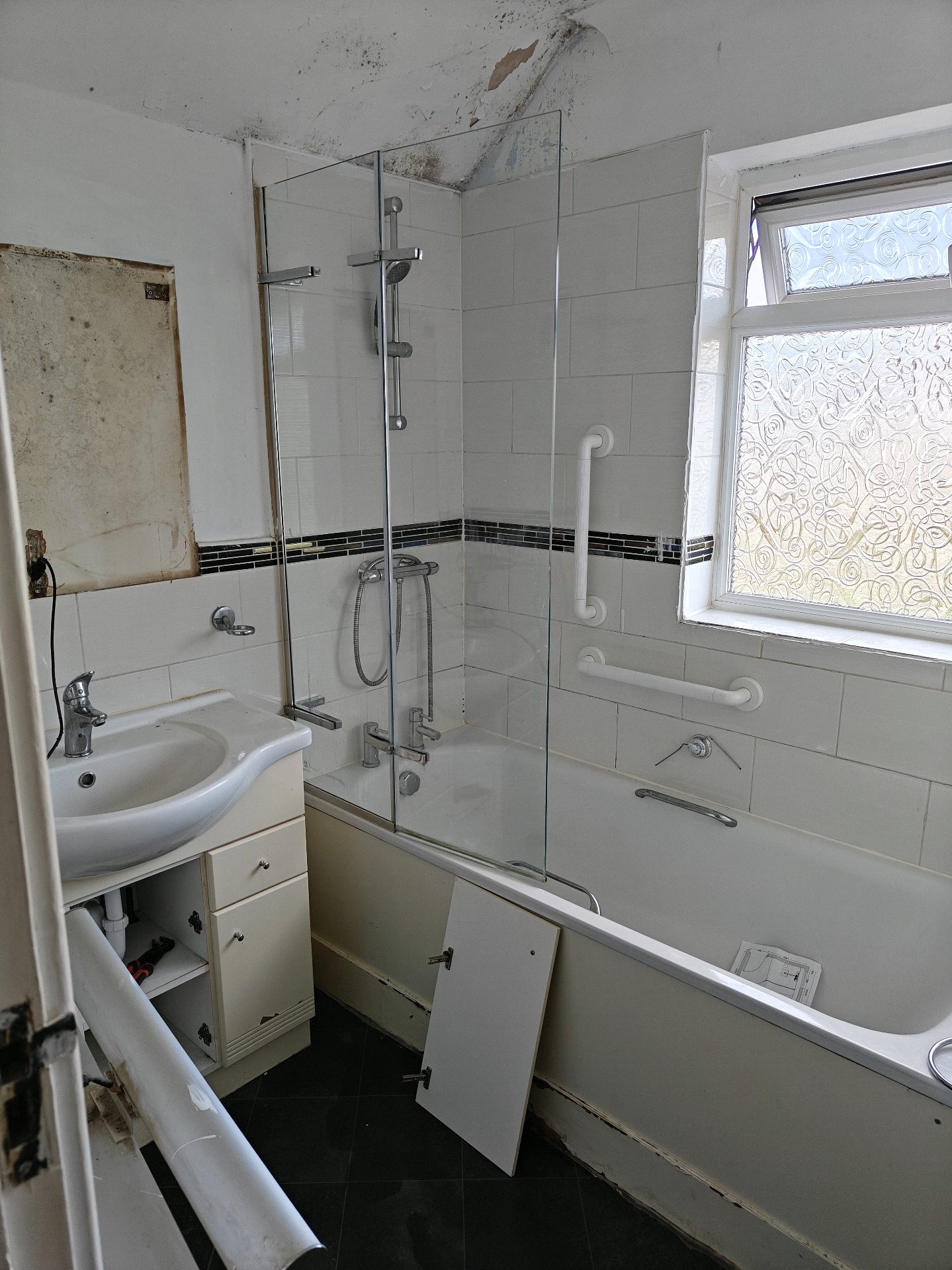 Before: Dated bathroom with mould on ceiling, old vanity unit, worn bath panels