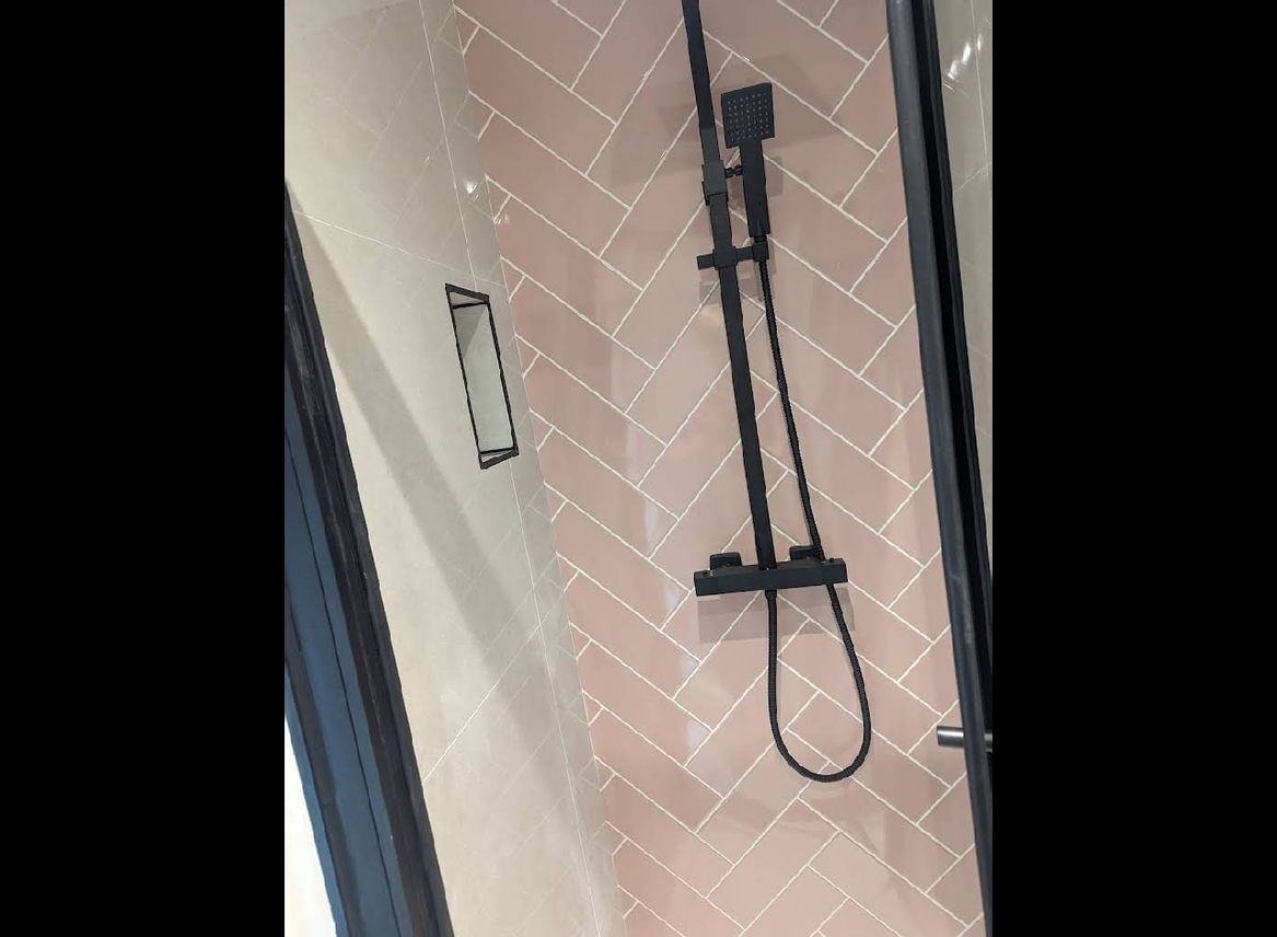 Pink herringbone tiles with black shower fixtures