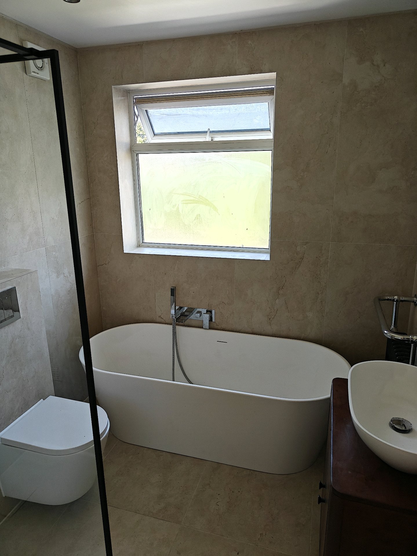 Sandstone bathroom wide view with wooden vanity and towel radiator